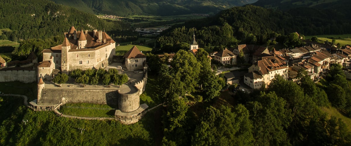 A historic castle surrounded by lush green hills and a valley.