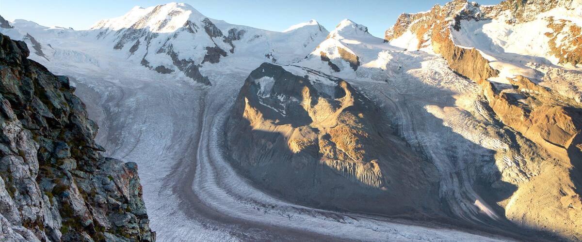 En glaciär med sprickor och ett bergigt landskap.