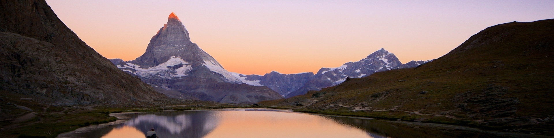 A group of people by a lake with a mountain in the background.