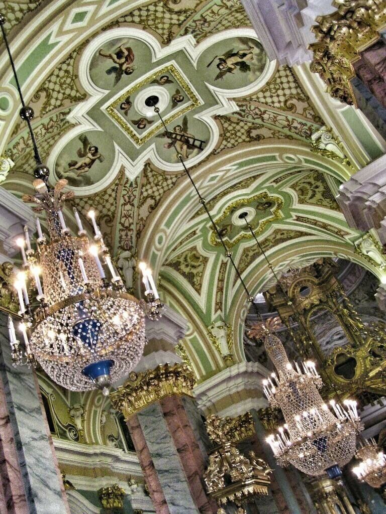 The interior of the cathedral is comfy and brightly colored. It is built in Baroque style.

Source: http://www.saint-petersburg.com/cathedrals/Peter-Paul-Cathedral.asp
The inside of the cathedral holds a fantastic iconostasis, completed by a group of more than forty Moscow architects under Ivan Zarudny from 1722-1727. Whereas the architectural style of the cathedral is similar in style to the Lutheran church, the painting of the iconostasis is more in the spirit of Catholic Church icons. The walls of the cathedral are also embellished with paintings of various bible themes, including many paintings of gospel stories by artists of the early and mid 18th century.