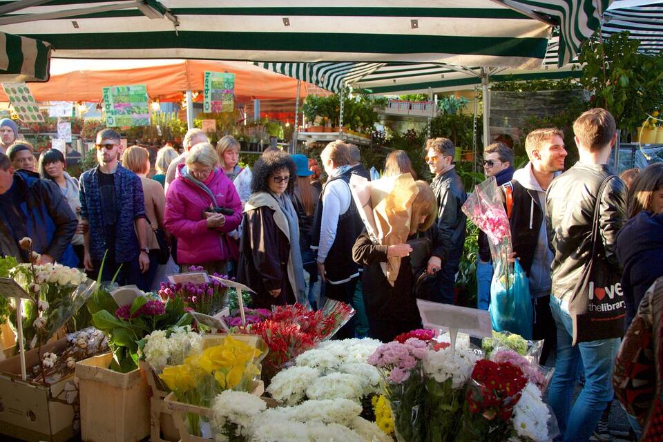 A crowded outdoor market with various stalls selling flowers and plants.