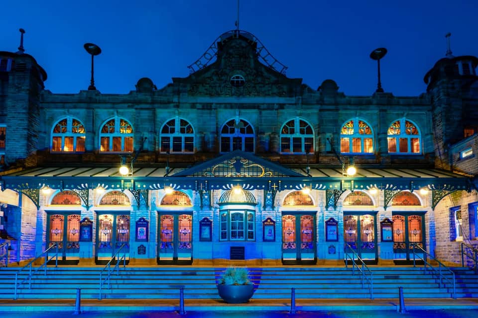 A historic building with arched windows and a central dome, illuminated by blue lighting.