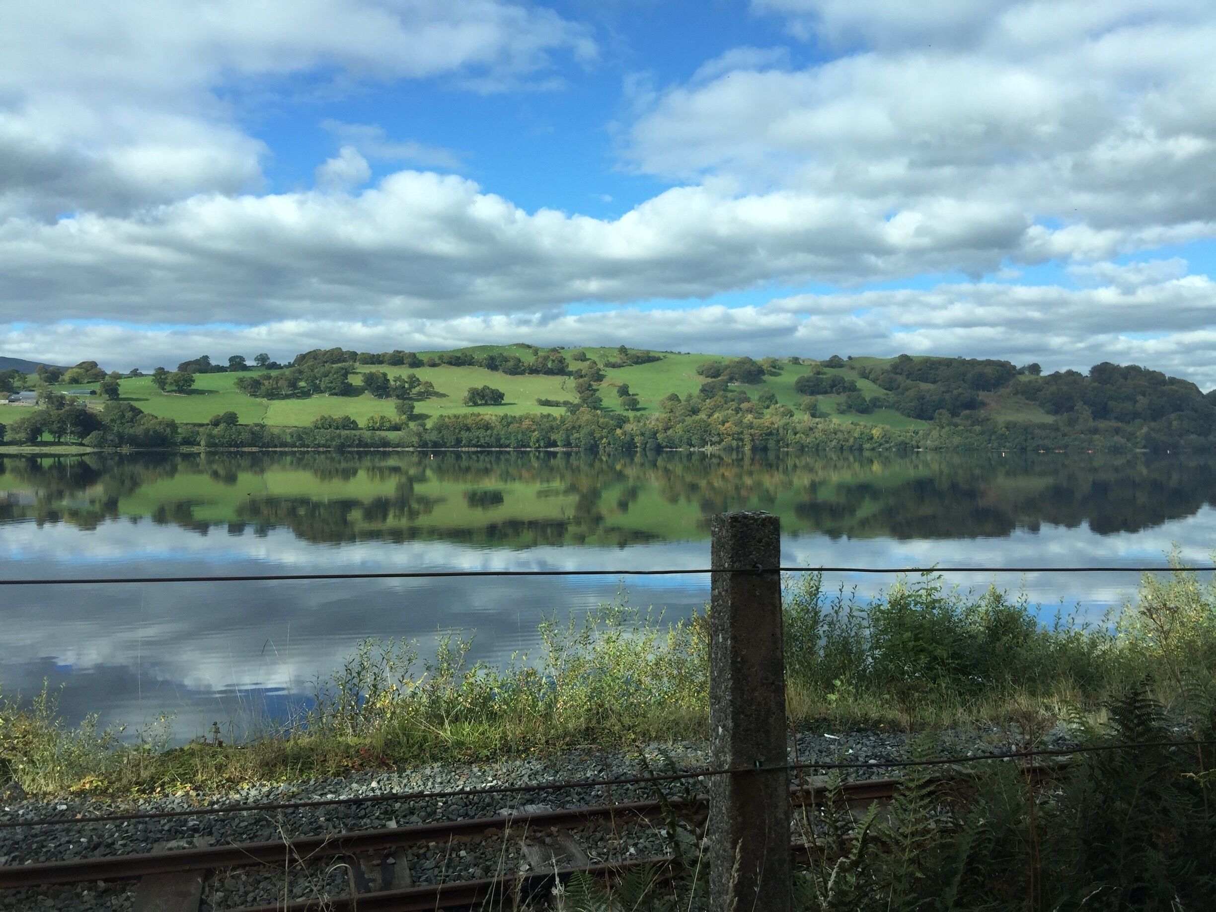 A lake reflecting the sky and surrounding hills.