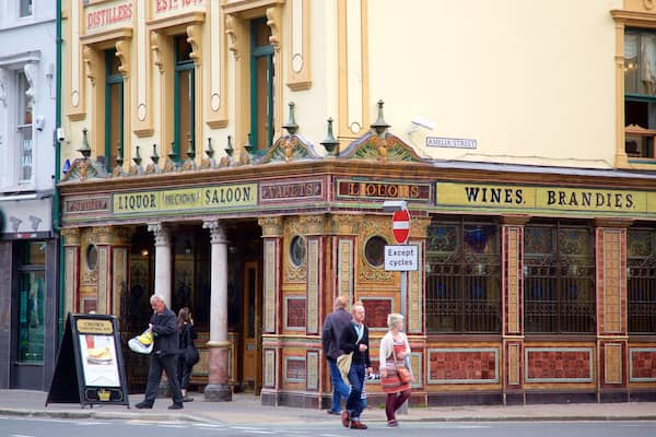 Um edifício histórico com arquitetura ornamentada, incluindo colunas e molduras decorativas. A fachada exibe placas com os dizeres 'Spirits', 'Liquor', 'The Crown', 'Saloons', 'Vaults', 'Liquor', 'Wines', 'Brandy' e 'Whiskey'.