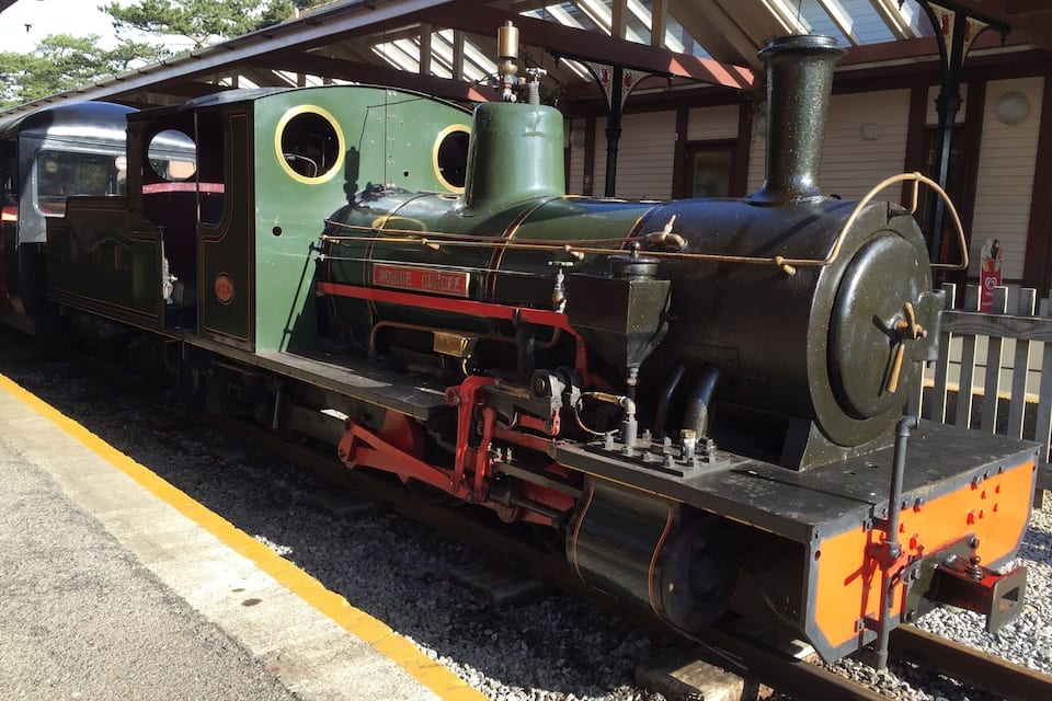 A vintage steam locomotive at a train station with a covered platform.
