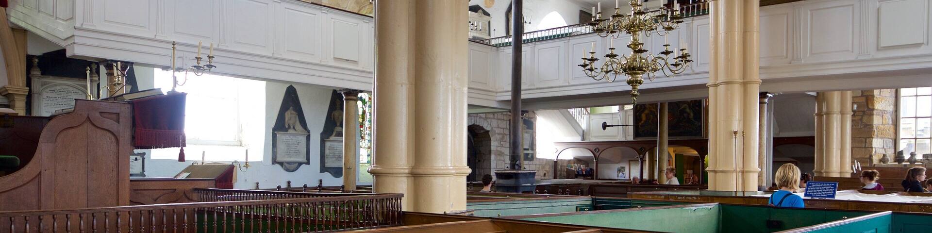 A grand hall with high ceilings, large columns, and a chandelier.