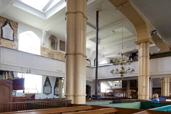 A grand hall with high ceilings, large columns, and a chandelier.