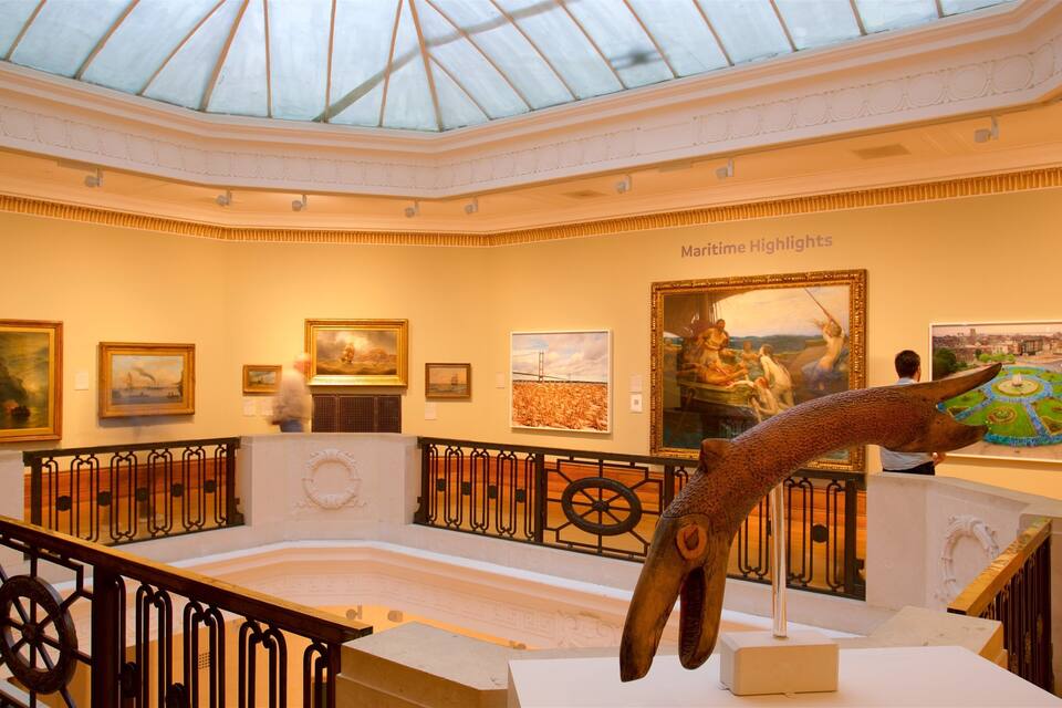 Ein Museuminnenraum mit Gemälden zum Thema Seefahrt, einer großen Skulptur und einer Glaskuppel.