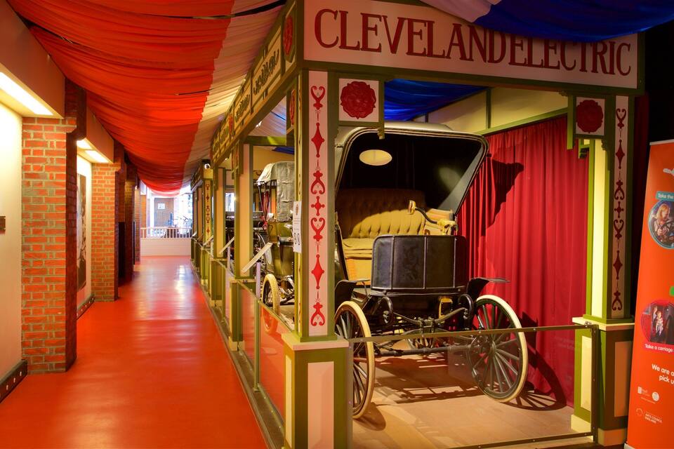 A museum exhibit with a vintage car and a red curtain backdrop.