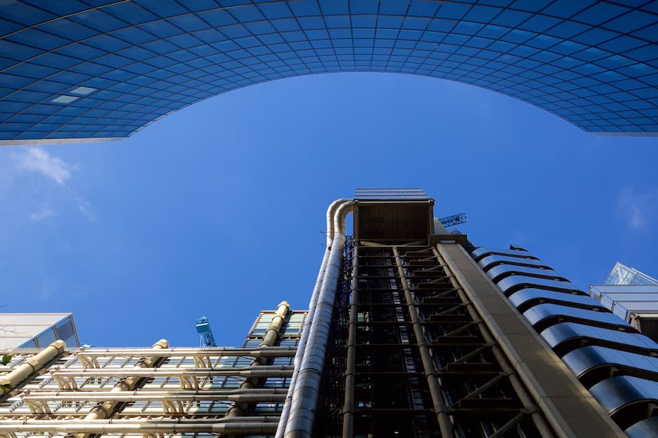 A modern building with a curved glass roof and a series of vertical pipes.