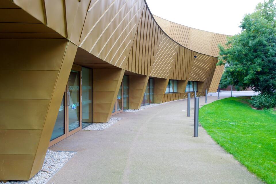 A modern building with a curved facade and a pathway leading to it.