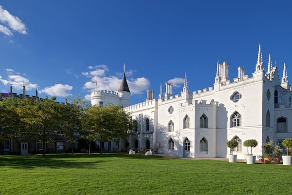A large white castle with multiple towers and spires, surrounded by a well-maintained lawn and trees.