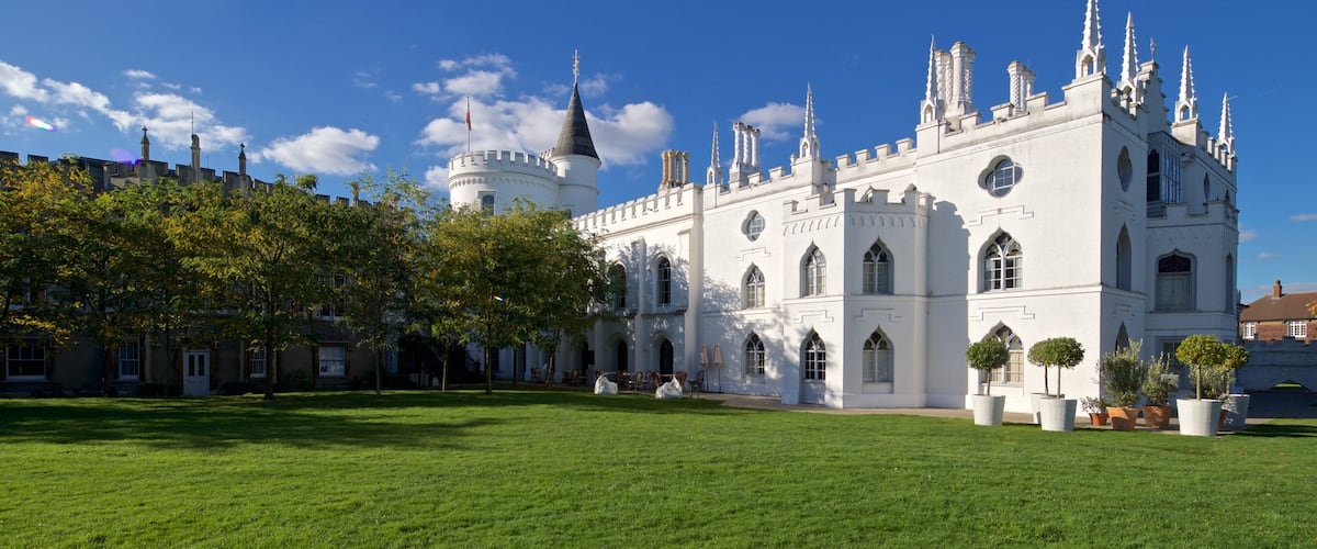 A large white castle with multiple towers and spires, surrounded by a well-maintained lawn and trees.