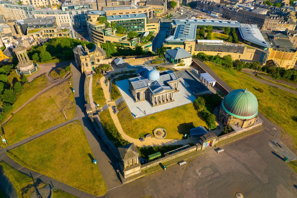 Vista aerea di una città con edifici moderni, una grande cupola e un monumento circolare.