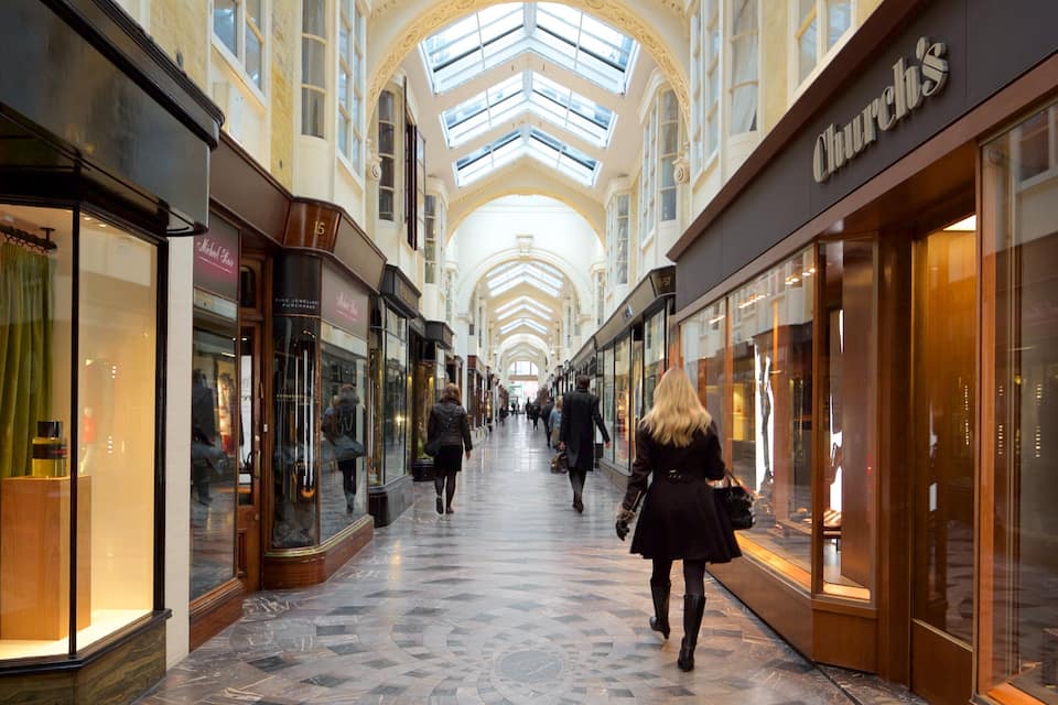 Un centro comercial con techos altos y tragaluces, que cuenta con tiendas como 'Church's' y 'Sally's'.