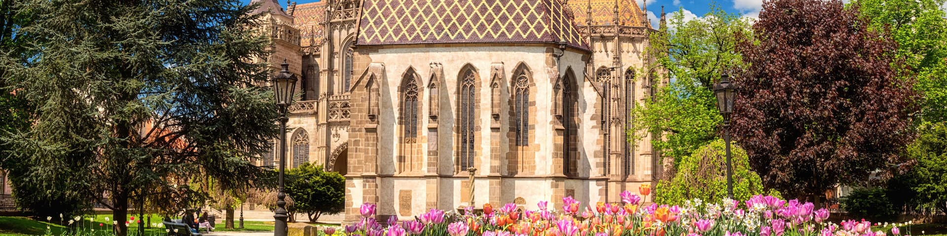 St. Michael chapel and St. Elisabeth cathedral in Kosice, Slovakia (Slovensko). Beautiful daytime cityscape in sunlight with flowers and blue sky with clouds