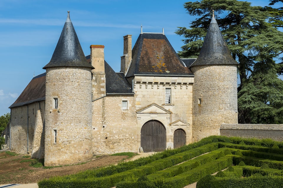 A historic stone castle with multiple towers and a well-maintained garden.