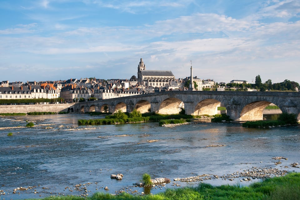 Un pont de pierre enjambant une rivière, avec une vue sur la ville en arrière-plan.