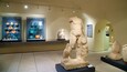 Una exhibición de museo con cerámica antigua y esculturas de piedra.