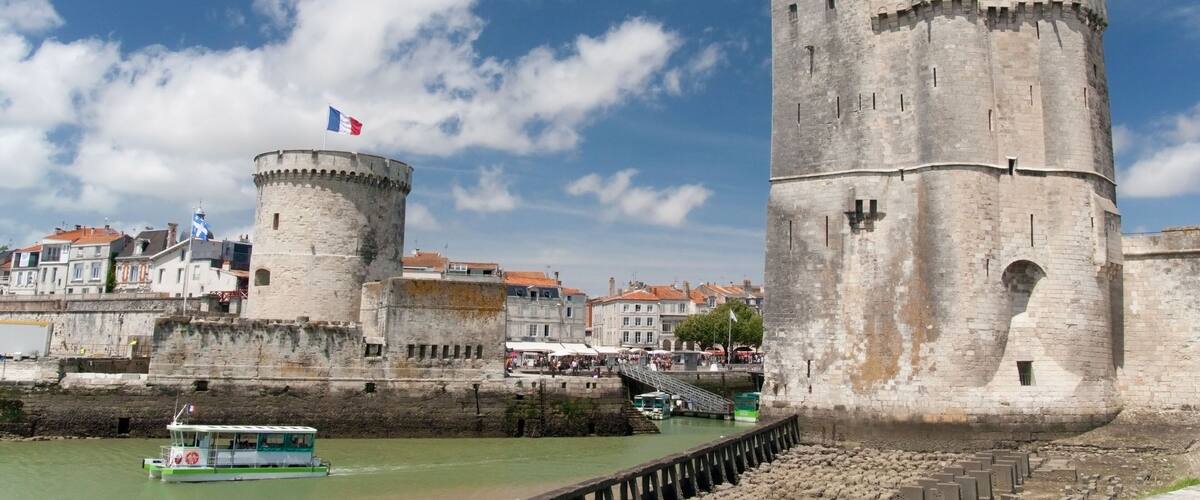D046A4 A water taxi exiting between the twin towers of the Vieux Port or old harbour in La Rochelle