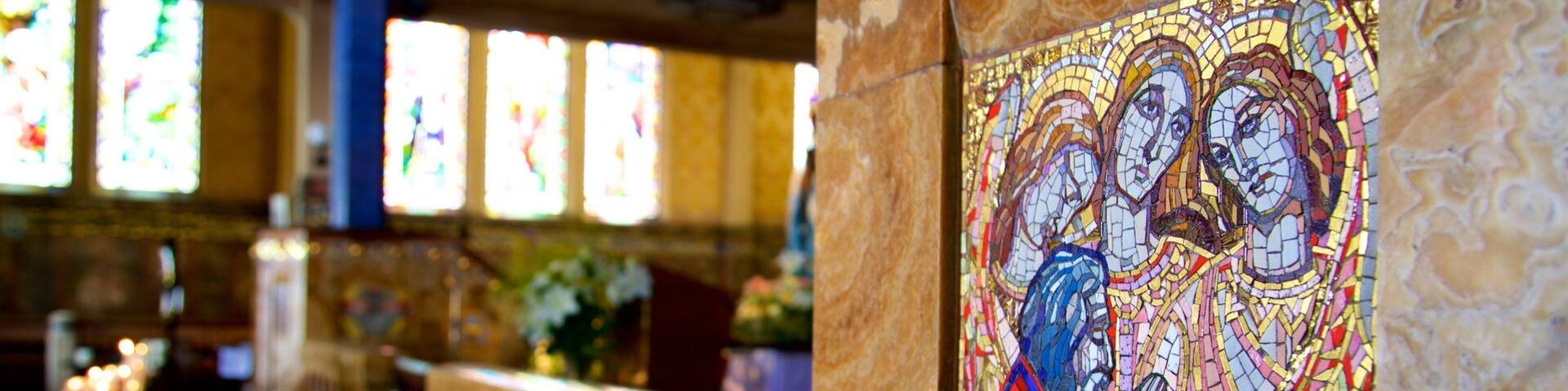 A church interior with stained glass windows and a mosaic.