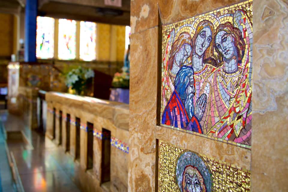 L’intérieur d’une église, avec des vitraux et une mosaïque.