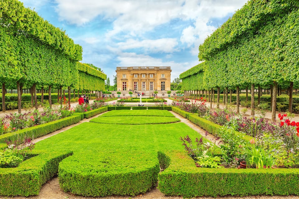 Ein prachtvolles Gebäude mit symmetrischen Gärten, ordentlich geschnittenen Hecken und einer Vielfalt bunter Blumen.