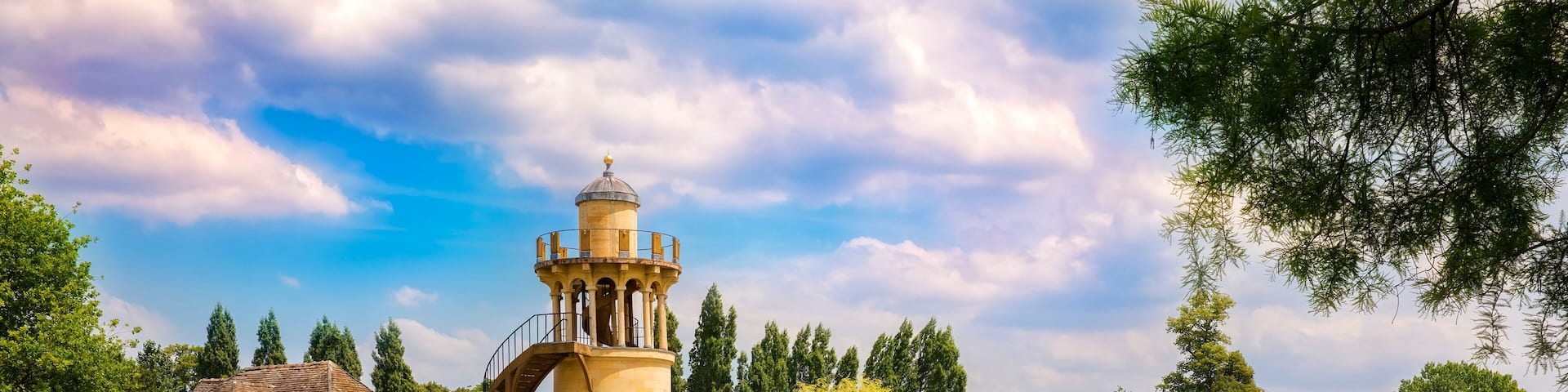 Un complejo de edificios históricos con una torre, un estanque y árboles circundantes.
