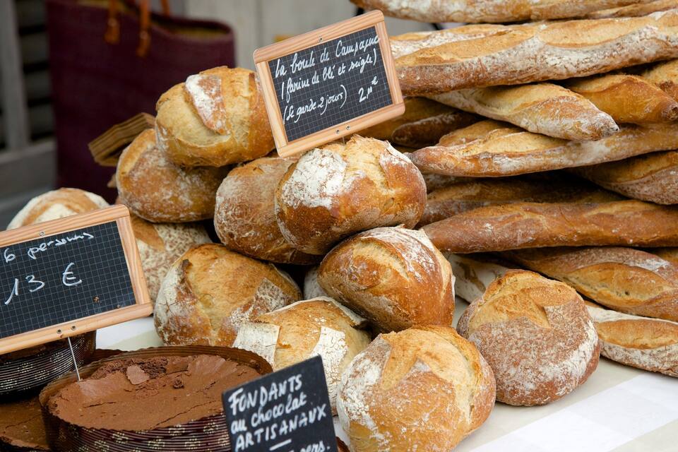 A variety of baguettes and other breads displayed at a bakery, with price signs in French.