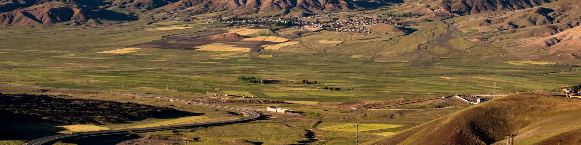 A snow-capped mountain, a valley with fields, and a small settlement.