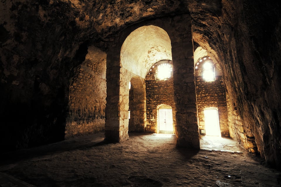 An ancient stone corridor with arched ceilings and a central doorway.