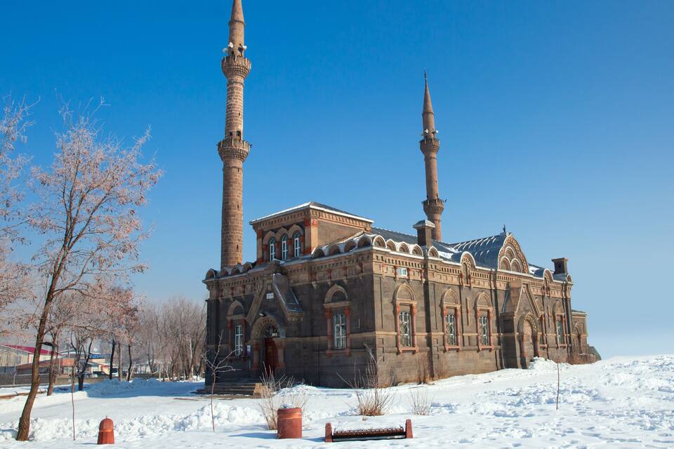 A historic building with two tall minarets and a snow-covered landscape.