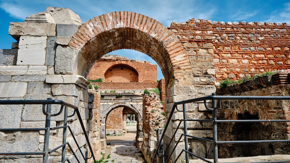 An ancient stone archway leading to a brick structure.