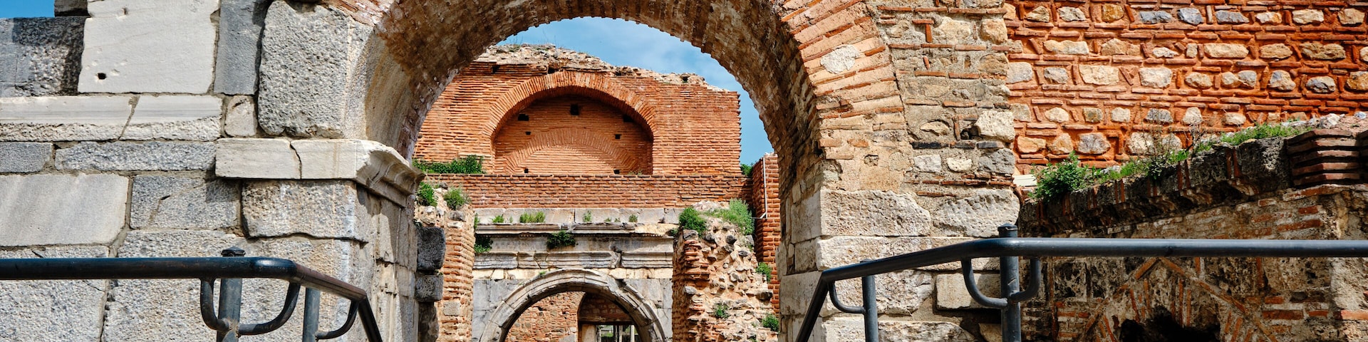 One of the entrance gate of ancient city of iznik (nicaea) made of red bricks stones city walls and stairs by taken photo during sunny day and ancient architecture arch and sky low angle photo.