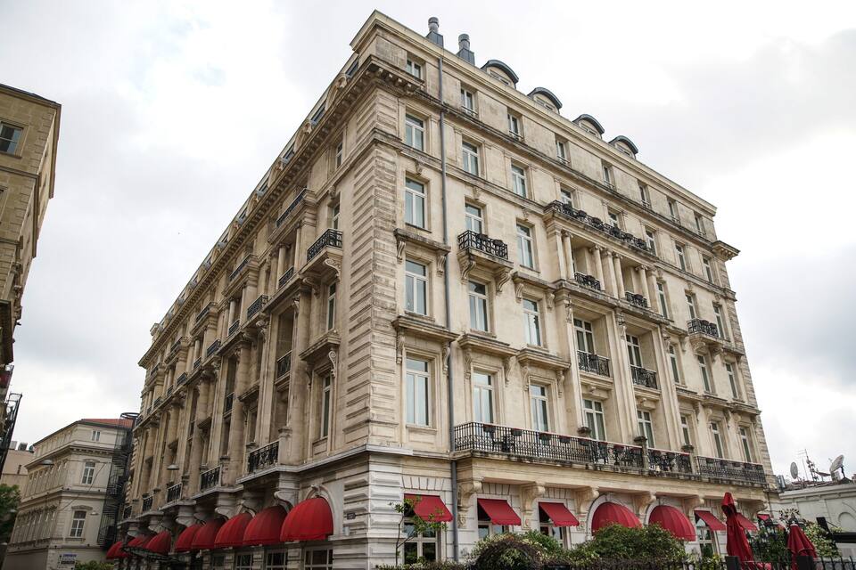 A historic building with classical architecture, red awnings, and multiple balconies.