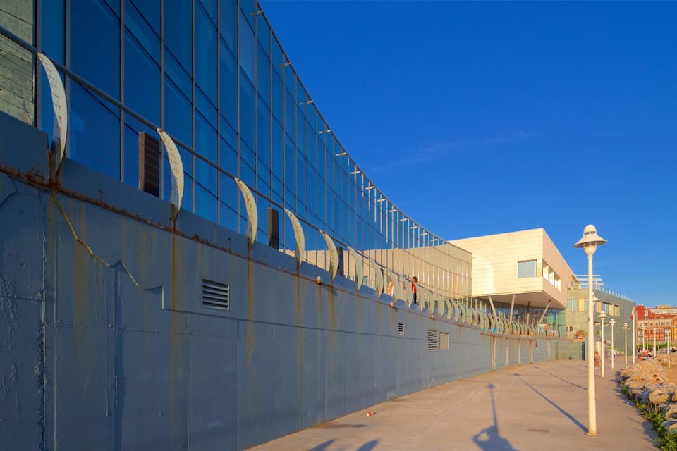 A modern building with a blue facade and a white structure with a sloped roof.
