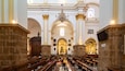 Interior d'una església amb pews de fusta, un altar central i una làmpada.