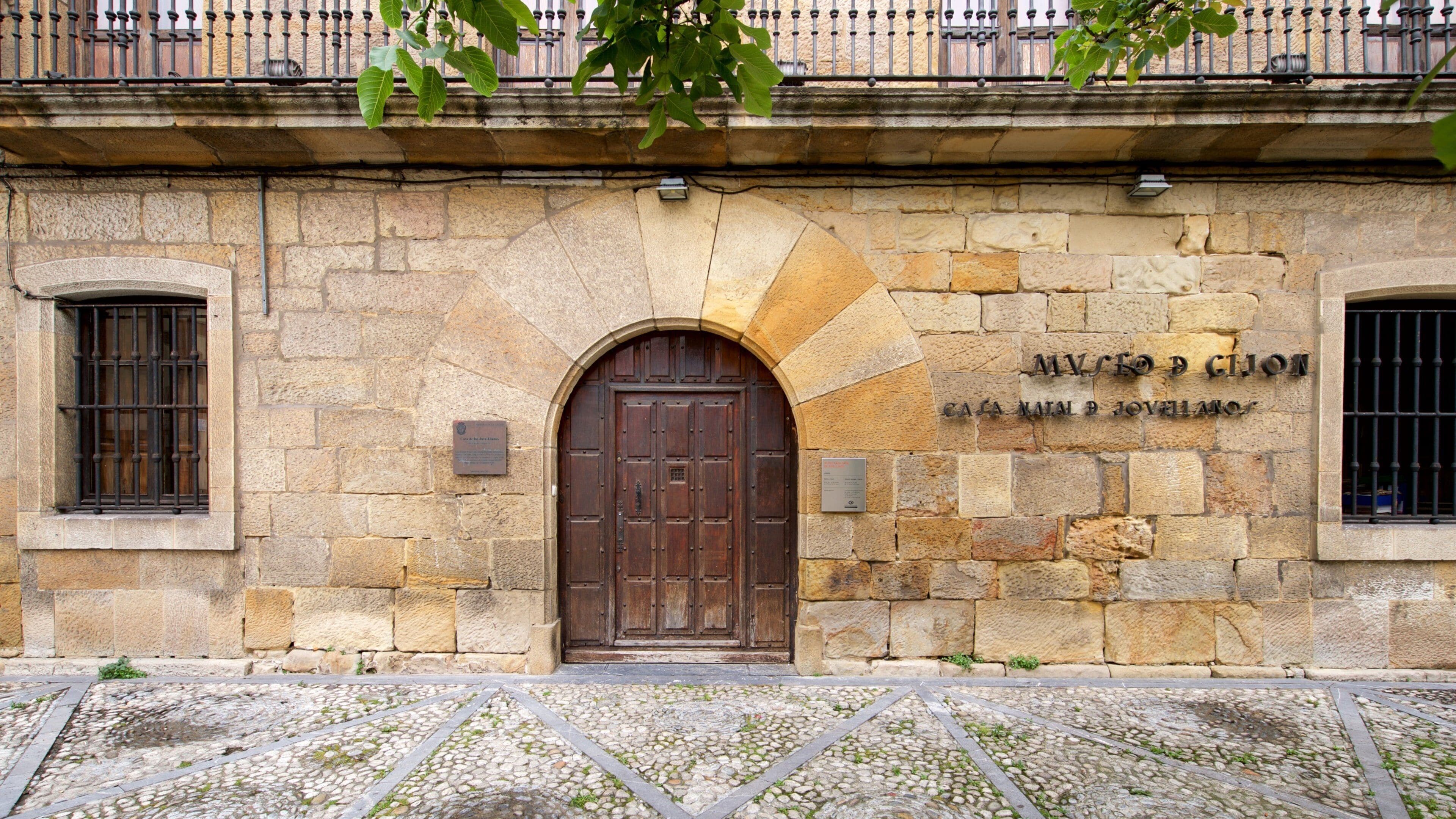 A stone building with a large wooden door and a plaque reading "Museo de la Casa de Pilatos".