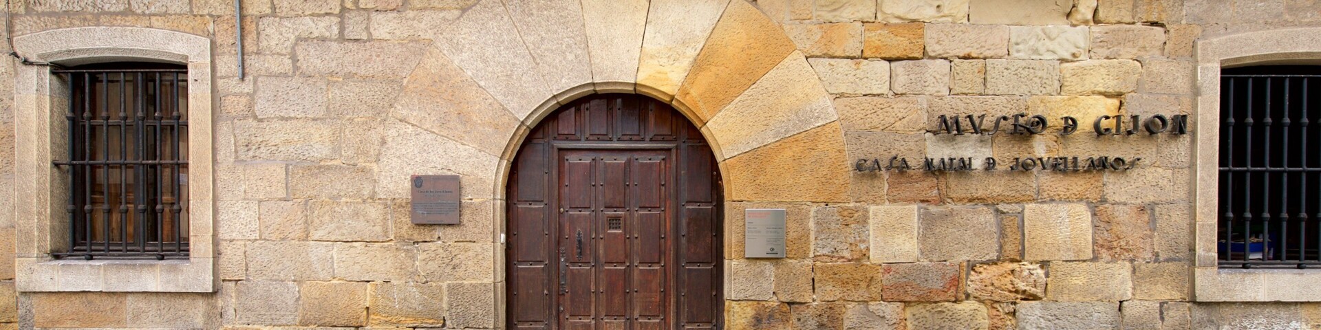 A stone building with a large wooden door and a plaque reading "Museo de la Casa de Pilatos".