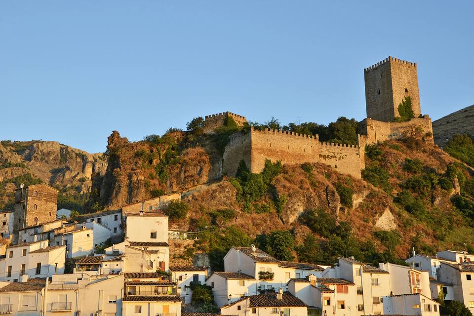 Una colina histórica fortificada con una torre destacada, rodeada de edificios blancos tradicionales.