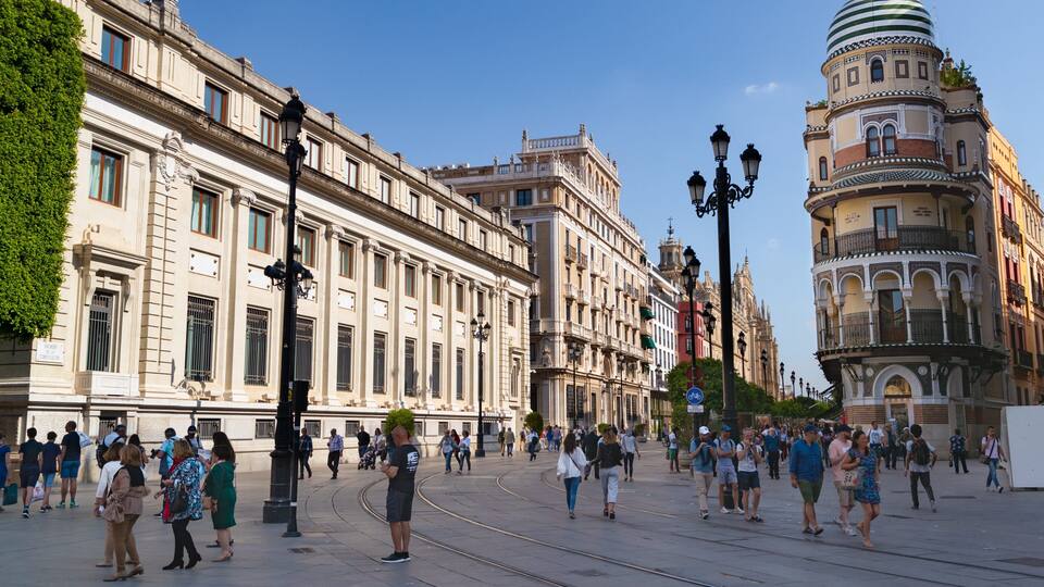 A bustling square with historic buildings, a tram line, and a prominent tower.