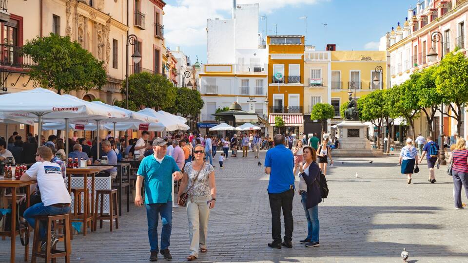 A bustling outdoor café area with people walking and sitting.