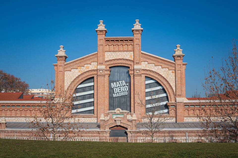 Um edifício grande de tijolos com janelas em arco e uma placa de destaque com a inscrição "Mata-Dero Madrid".
