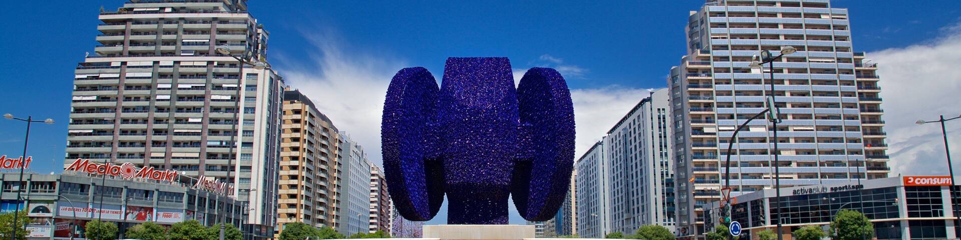 Una gran escultura azul en una plaza urbana rodeada de edificios altos.