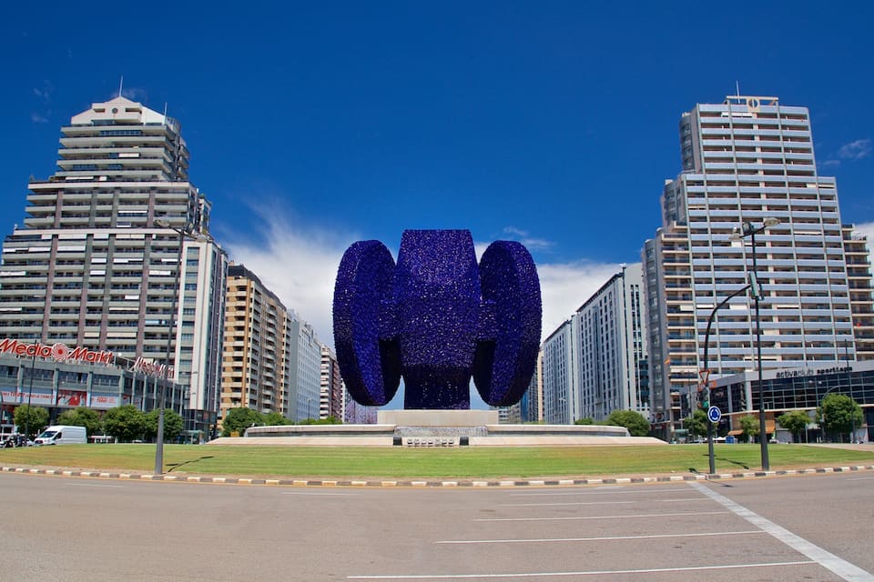 Una gran escultura azul en una plaza urbana rodeada de edificios altos.