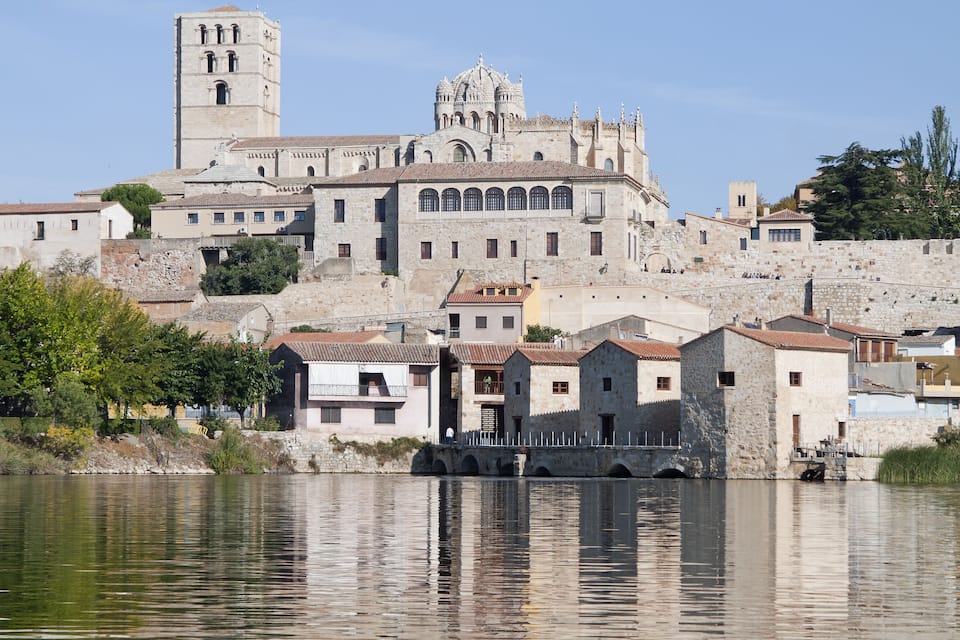 A historic town with a prominent church and bell tower, situated by a calm river.