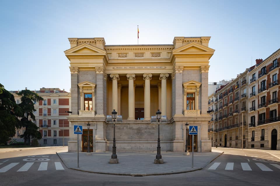 Un edifici neoclàssic amb columnes i un frontó central, envoltat d'edificis urbans.