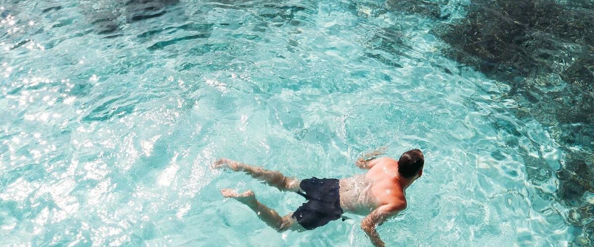 A person swimming in clear turquoise water.