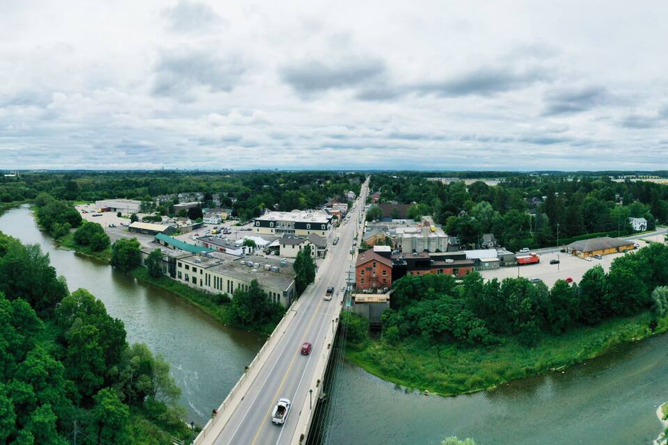 Une rivière traverse une ville où se trouve un pont, le tout étant entouré d’une végétation luxuriante.