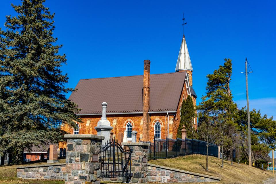 Une église en briques, dotée d’un clocher et d’une clôture en pierre à l’avant.
